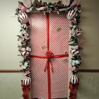 A beautifully decorated door that resembles a giant gift, complete with festive garlands and ornaments.