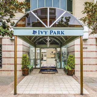 The entrance to a building named Ivy Park, featuring a covered walkway and potted plants on either side.