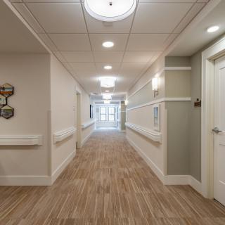 A well-lit hallway in a building with wooden flooring and multiple doors.