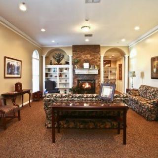 A cozy living room with a central fireplace, surrounded by comfortable furniture and decorative shelves.