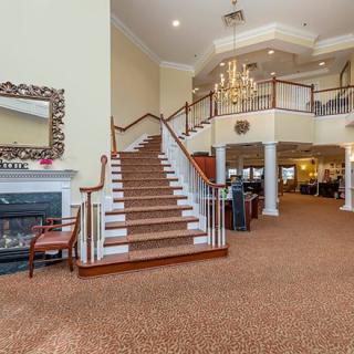 A spacious lobby with a grand staircase, chandelier, and a cozy fireplace.