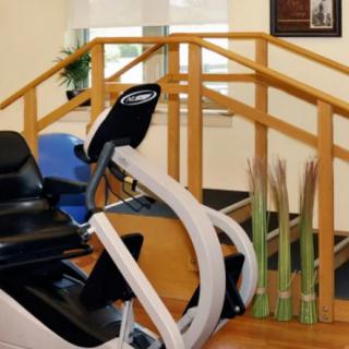 A therapy room with exercise equipment and wooden stairs for rehabilitation exercises.