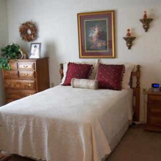 A cozy bedroom with a neatly made bed, decorative pillows, and classic furniture.