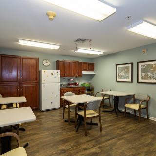 A communal kitchen and dining area with tables, chairs, and kitchen appliances.