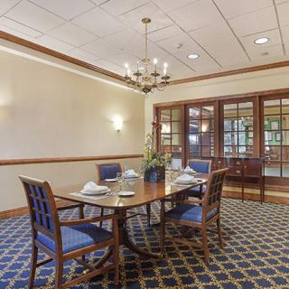An elegantly decorated dining room with a wooden table, upholstered chairs, and a chandelier.