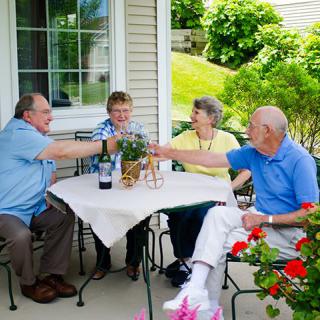 A group of seniors enjoying a social gathering on a patio, raising glasses in celebration.