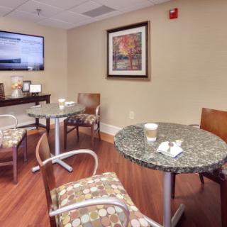A cozy waiting area featuring chairs and tables, complemented by artwork and a television.