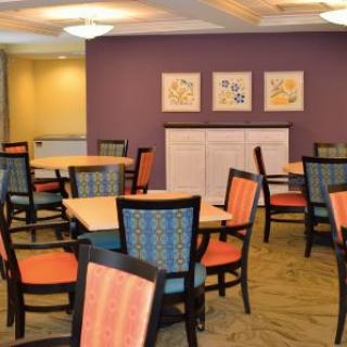 A dining area with colorful chairs and tables, featuring a purple accent wall adorned with artwork.