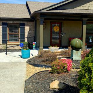 A well-maintained front yard featuring a decorative sphere and vibrant plants.