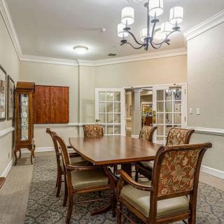 A well-furnished dining or meeting room featuring a wooden table, upholstered chairs, and an elegant chandelier.