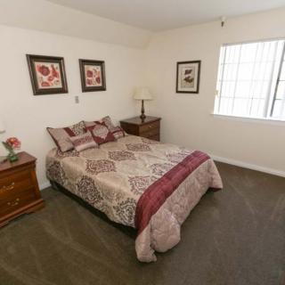 A cozy bedroom with a neatly made bed, nightstands, and framed artwork on the walls.
