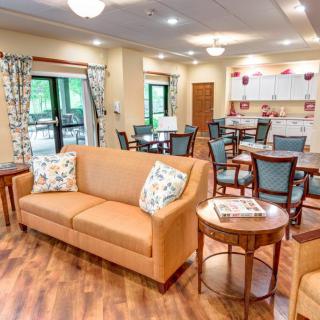 A cozy living and dining space with a sofa, tables, and chairs in a brightly lit room.