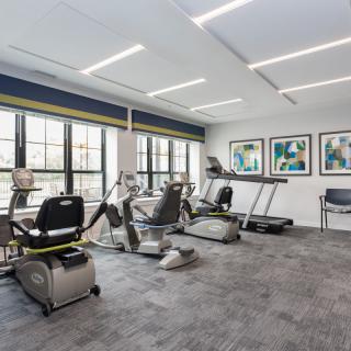 A modern gym with various exercise equipment and large windows.
