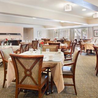 An elegant dining room with neatly arranged tables and chairs in a warm, neutral color palette.