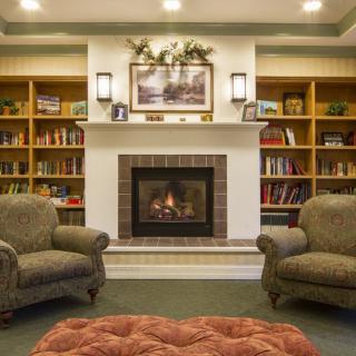 A cozy living room featuring a fireplace flanked by bookshelves and two comfortable armchairs.