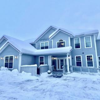 A two-story blue house covered in snow during winter.