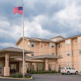 A hotel building with an American flag flying in front, under a cloudy sky.