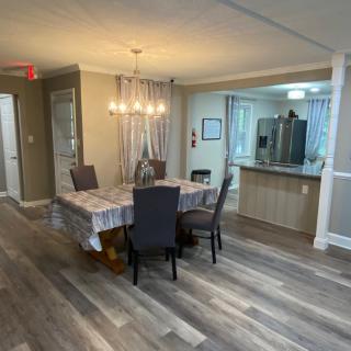 A modern dining area with a table set for six, adjacent to an open kitchen.