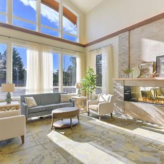A modern and bright living room with large windows and a cozy fireplace.