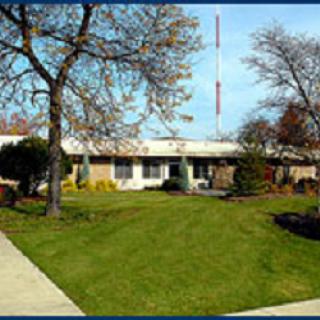 A well-maintained building surrounded by green grass and trees.