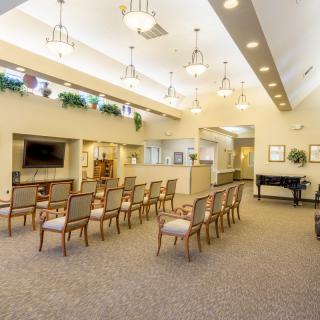 A spacious and modern seating area with rows of chairs, a piano, and contemporary lighting.