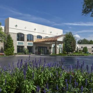 A modern building surrounded by a landscaped garden with flowers under a clear blue sky.