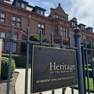 A historic building with a sign labeled 'Heritage on the Marina' behind a decorative fence.
