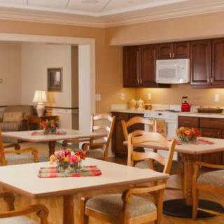 A cozy dining area with wooden tables and chairs, adjacent to a kitchen space.