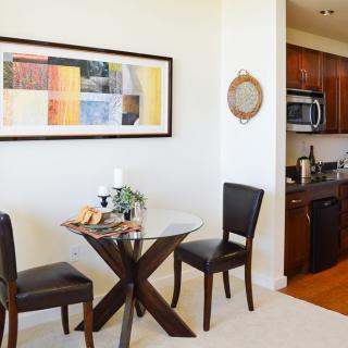 A cozy dining area with a small round table and two chairs, adjacent to a modern kitchen.