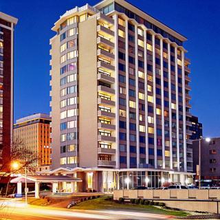 A brightly lit high-rise hotel building at night in an urban setting.