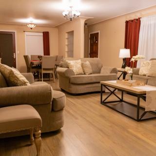 A cozy living room with a seating area and a dining space, featuring neutral tones and warm lighting.