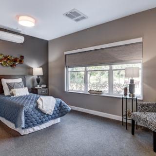A modern and cozy bedroom featuring a neatly made bed, stylish furniture, and ample natural light.