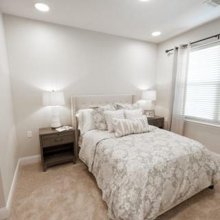 A cozy and well-decorated bedroom with a neatly made bed, nightstands, and lamps.