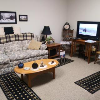A cozy living room with a floral sofa, coffee table, and TV setup.