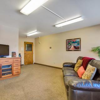 A cozy living room with a leather sofa, television, and artwork on the wall.