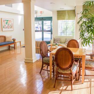 A cozy living room featuring a wooden dining table, elegant chairs, and abundant natural light.