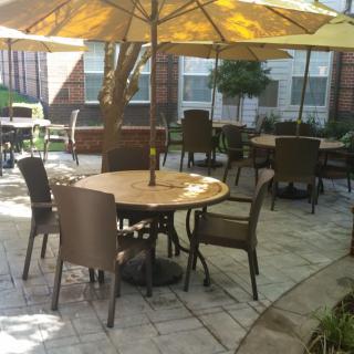 A peaceful outdoor patio area with tables, chairs, and umbrellas on a sunny day.
