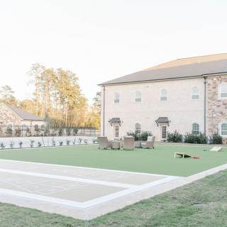 A spacious backyard features a well-maintained lawn and outdoor furniture, adjacent to a large building.