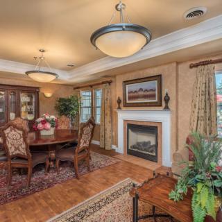 A beautifully furnished dining room with elegant chandeliers, a fireplace, and decorative artwork on the wall.