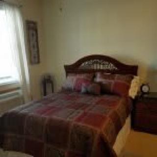A cozy bedroom with a neatly made bed and decorative pillows.