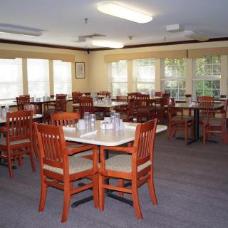 An empty dining room with neatly arranged tables and chairs, lit by natural light.