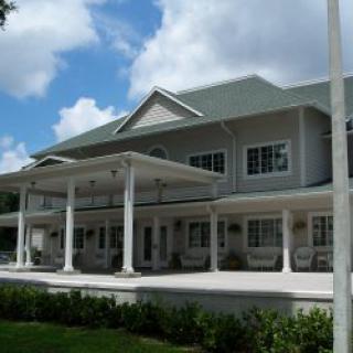 A large residential house with a covered porch and multiple columns.