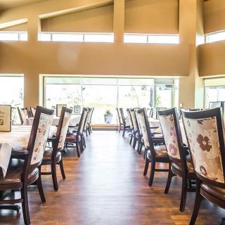A well-lit restaurant dining area with neatly arranged tables and chairs.