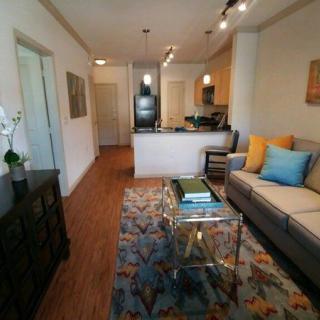 A modern living room with colorful accents and an open kitchen layout.
