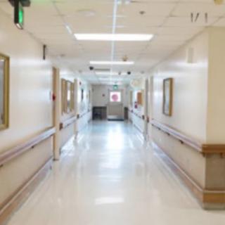 A clean and well-lit hospital corridor with framed pictures on the walls.