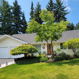 A charming single-story house surrounded by lush greenery and well-maintained landscaping.