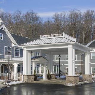 A residential building with a covered entrance and snowy surroundings.