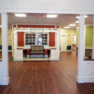 A welcoming lobby space with wooden flooring and bright lighting, featuring a reception area at the back.