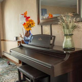 A beautifully decorated interior featuring a piano with vases of colorful flowers and a large mirror above.