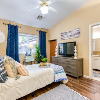 A modern and cozy bedroom with stylish decor, featuring a bed, television, and wood flooring.